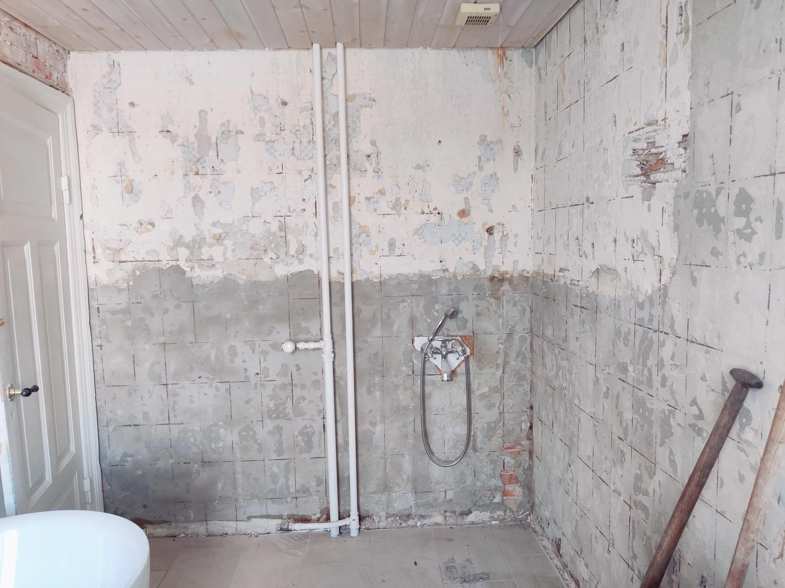 Badeværelse under renovering med blotlagte vægge og rør